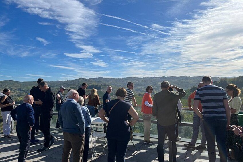 A group of people standing on a terrace overlooking a scenic landscape. 3