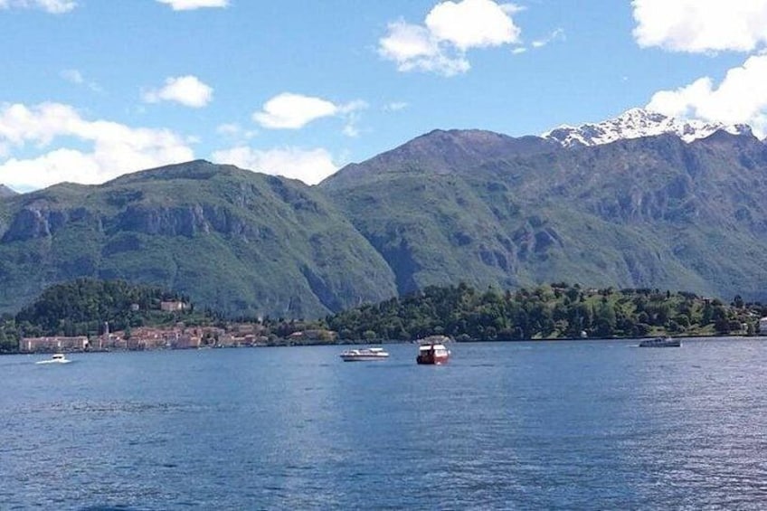 A lake with boats, a town, and mountains in the background. 5