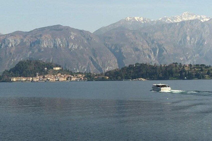 A lake with a boat, mountains in the background, and a town on the shore. 2