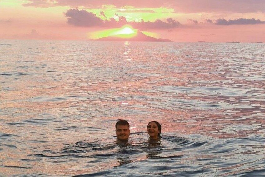 Two people swimming in the ocean with a sunset in the background. 4