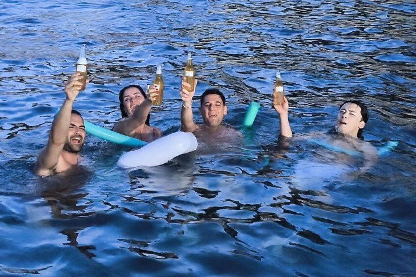People in water holding bottles, with a white inflatable object. 3
