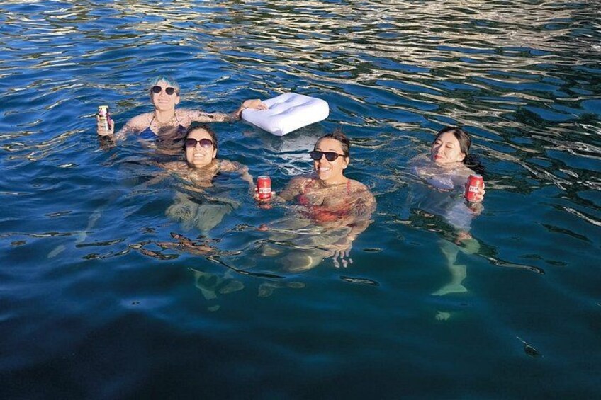People floating on water with drinks and an inflatable object. 2