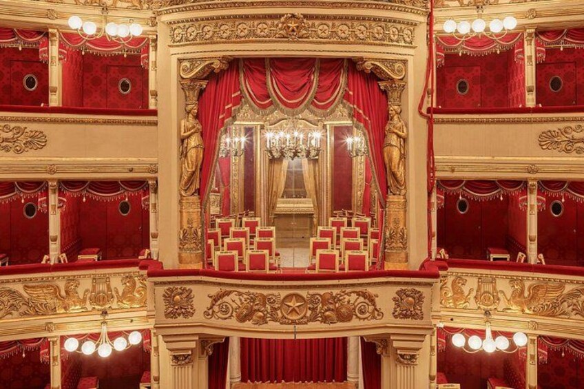 Een sfeervol theaterinterieur met fluwelen gordijnen, gouden accenten en een kroonluchter. 2