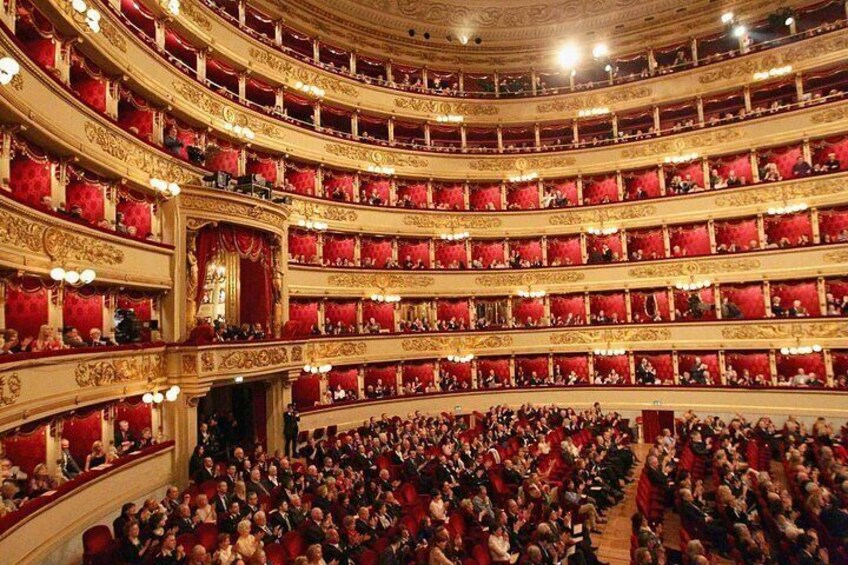 Un teatro imponente con varios balcones y filas de asientos rojos. 3