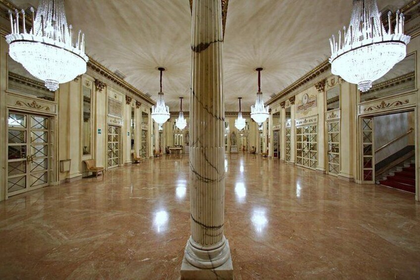 Un gran salón con suelos de mármol, columnas ornamentadas y grandes candelabros. 5