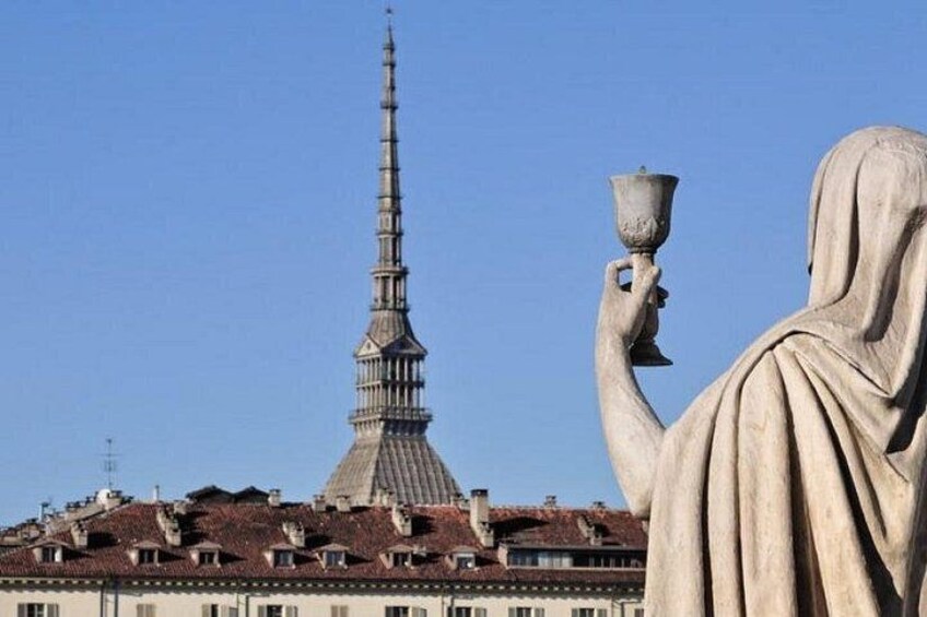 Una estatua sosteniendo una taza, una torre alta y un edificio con tejado rojo. 3