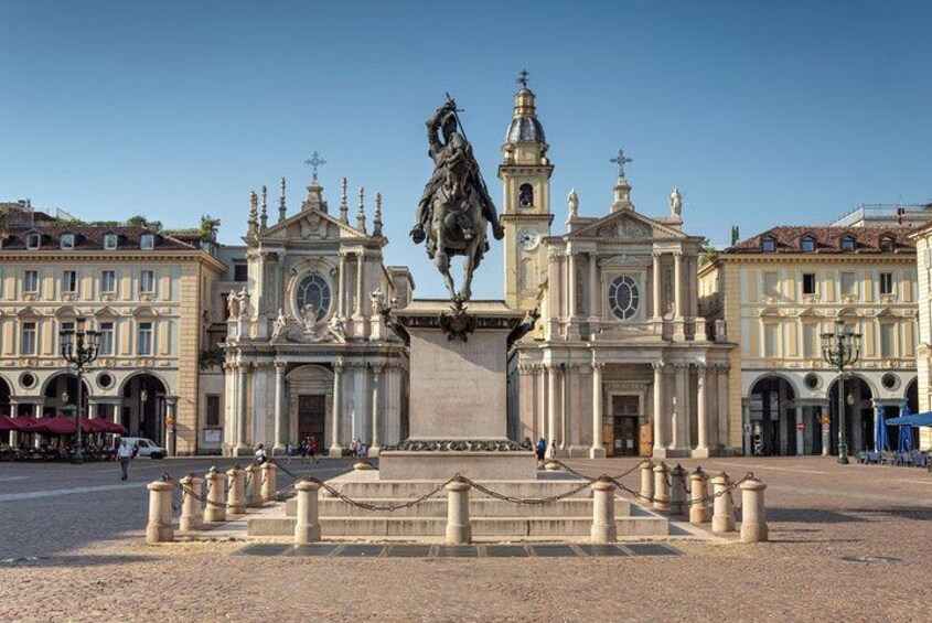 A historical plaza with a central monument, surrounded by classical buildings and a clear sky. 4