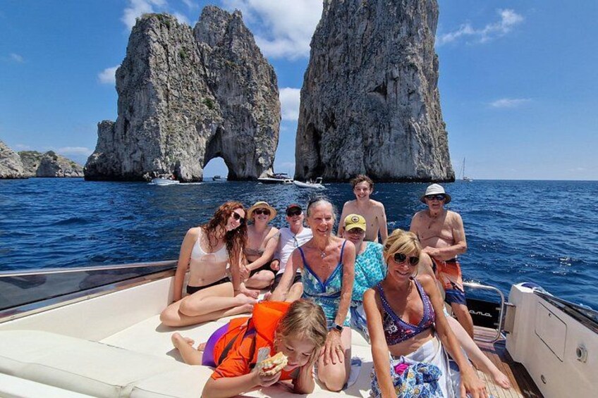 A group of people on a boat with a rocky arch formation in the background. 1