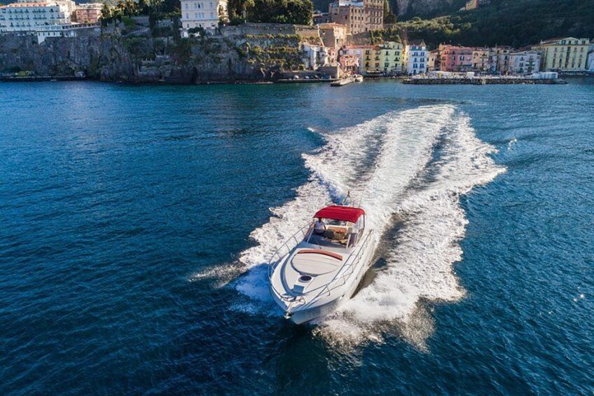 A speedboat with a red canopy moving through a body of water, creating a wake. 3