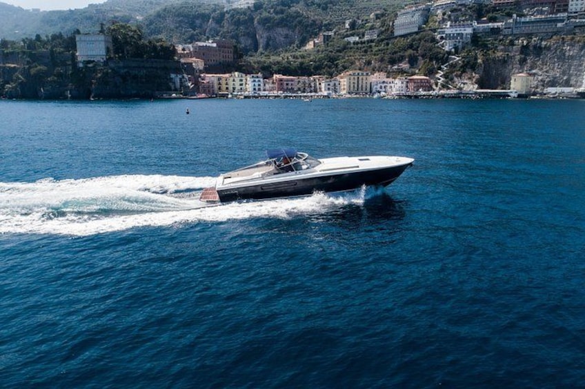 A speedboat on a calm body of water with a coastal town in the background. 5