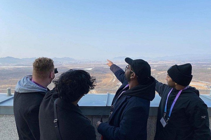 Four people standing on a balcony overlooking a landscape. 2