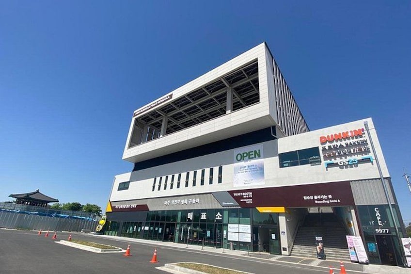 A modern building with a Dunkin' Donuts sign, a glass facade, and a clear blue sky. 2