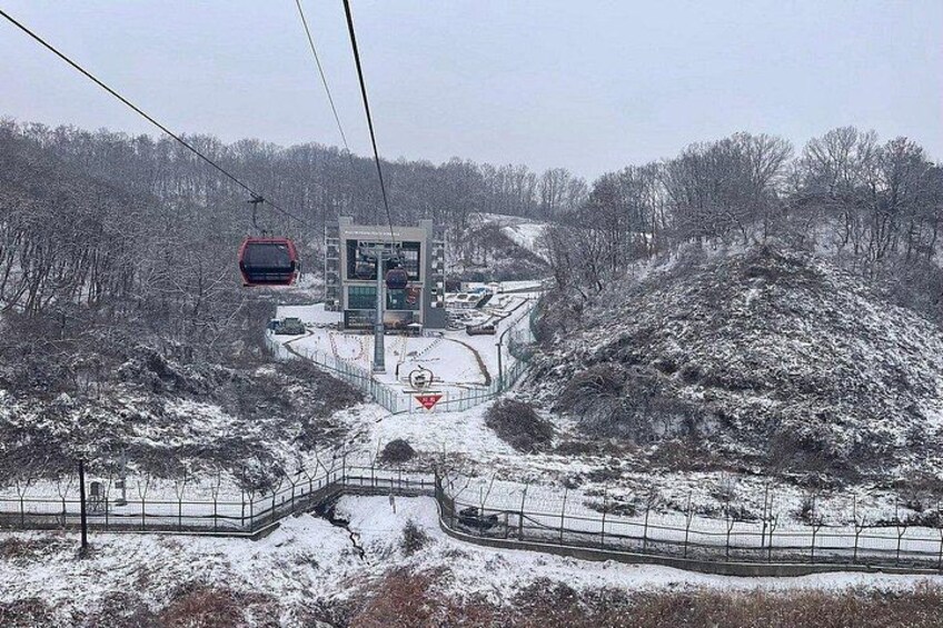 A snowy landscape with a ski lift, a building, and a fenced area. 4