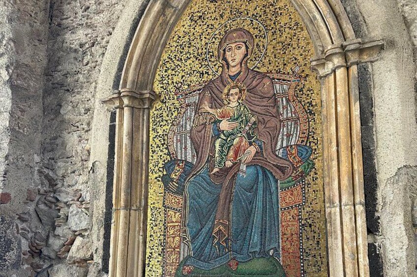 Un mosaico de una mujer sosteniendo a un niño, rodeado de patrones ornamentales y arcos arquitectónicos. 5