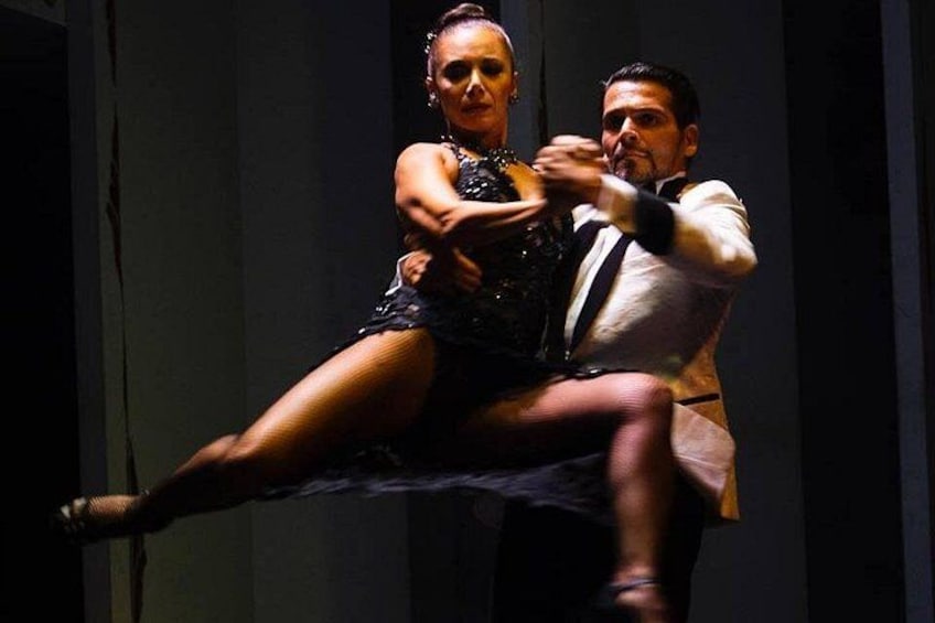 Une personne vêtue d’une robe noire effectue un mouvement de danse avec une autre personne portant une chemise blanche et un pantalon noir. 4