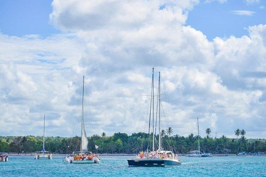 Ein klarer, blauer Himmel mit vereinzelten Wolken, ein ruhiges Meer und mehrere Segelboote mit Passagieren. 2