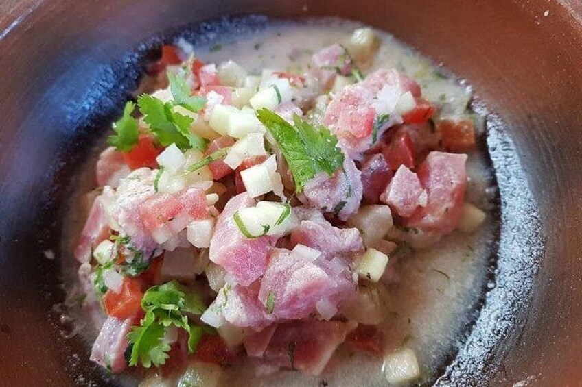 A bowl of ceviche with diced fish, tomatoes, onions, and cilantro. 3