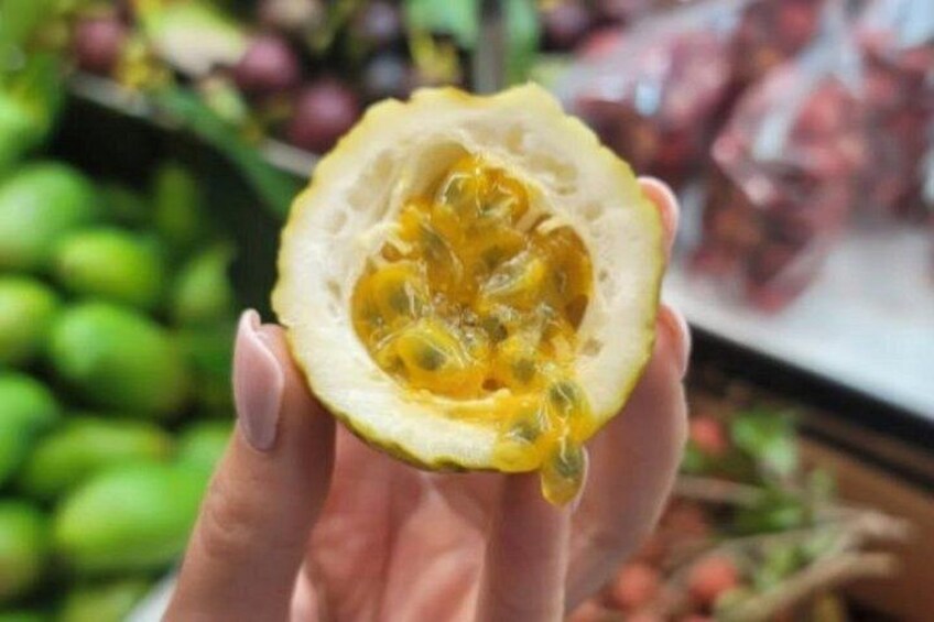 Una mano sosteniendo media fruta de la pasión, con semillas visibles. 4