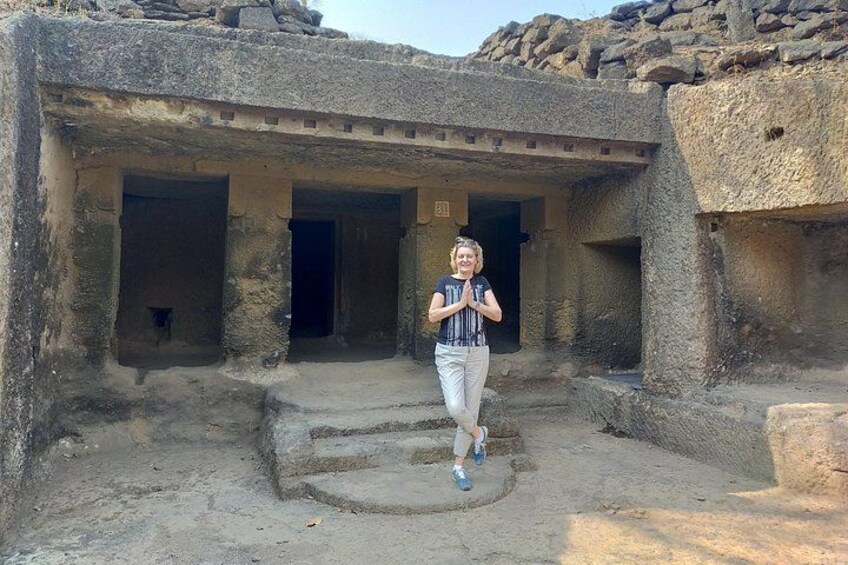 A person standing in front of an ancient stone structure with multiple doorways. 1