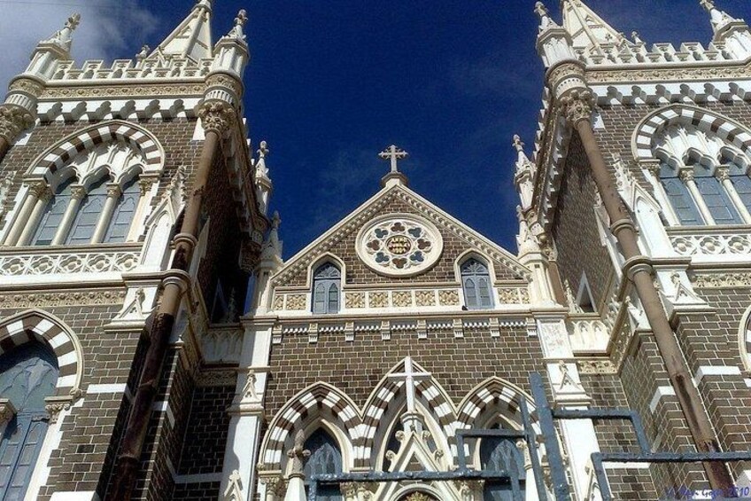 A Gothic-style church with intricate brickwork, pointed arches, and a prominent cross at the top. 2