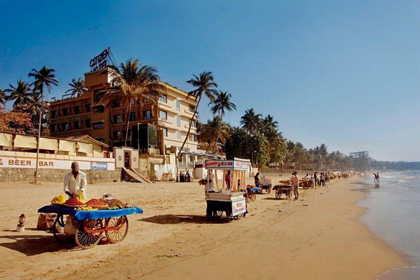 A beach with vendors, palm trees, and a building with a sign. 4