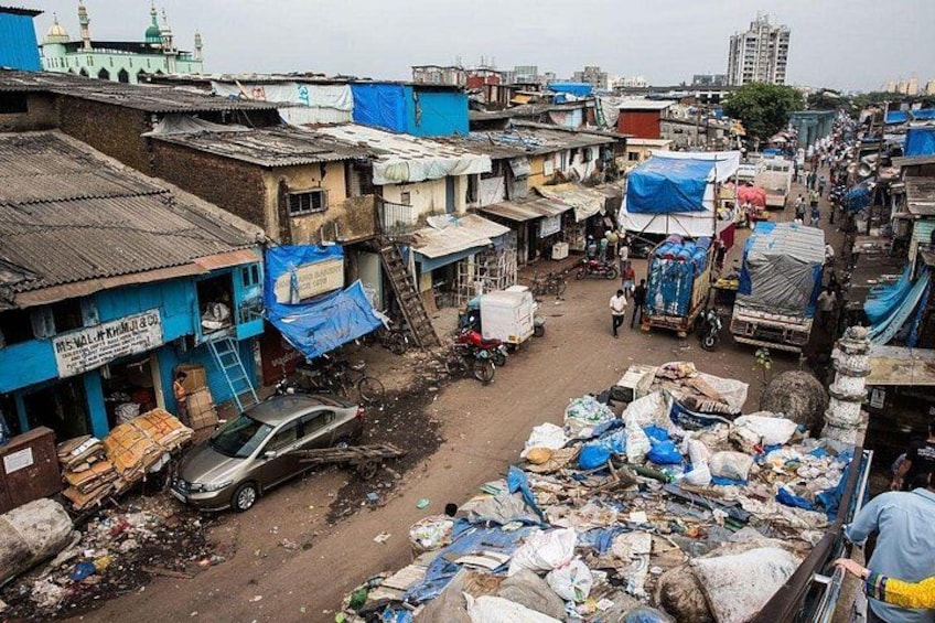 Una zona urbana densamente poblada con construcciones improvisadas, una calle abarrotada y una mezquita al fondo. 2