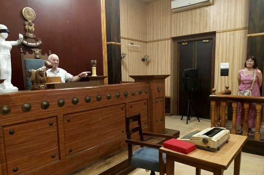 Een houten bureau met een rode doos, een stoel en een beeldje. 3