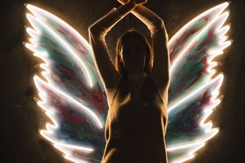 A person with glowing wings against a dark background. 2