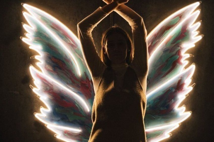 A person with glowing wings against a dark background. 2