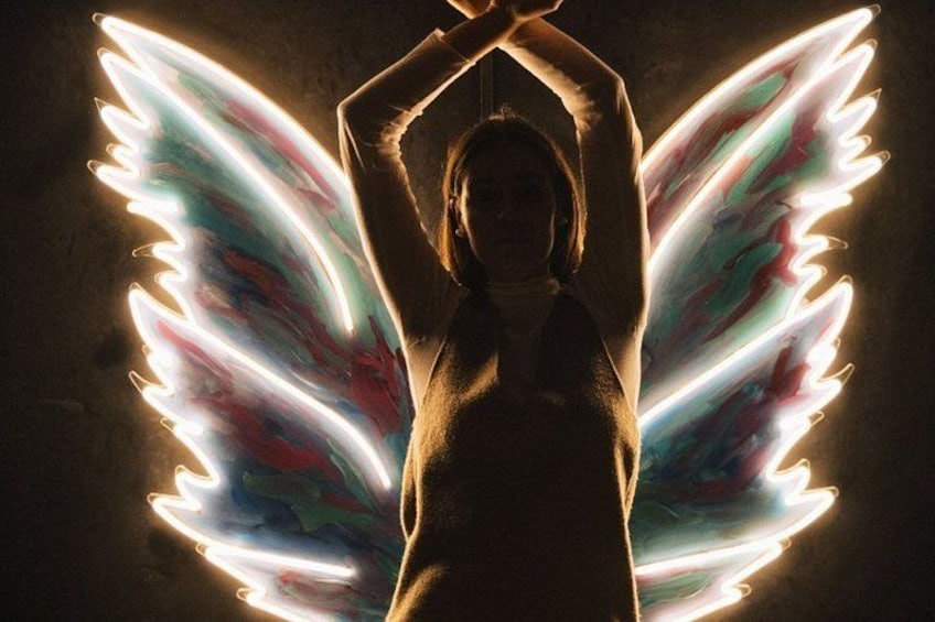 A person with glowing wings against a dark background. 2