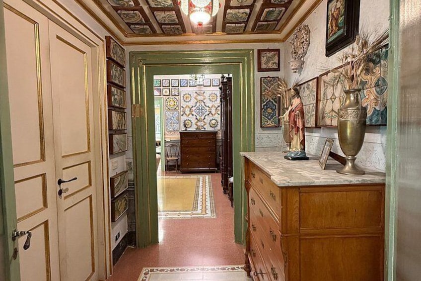 A hallway with patterned tiles, wooden cabinets, and a vase on a counter. 2