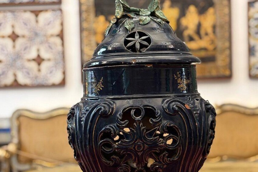 A decorative black urn with intricate designs and a lid with a star-shaped cutout. 5