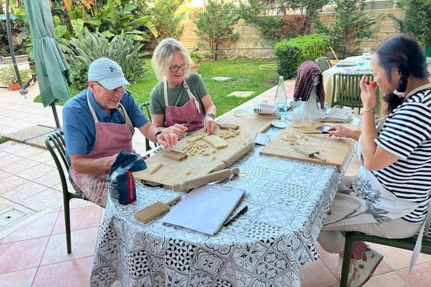 Tres personas sentadas a una mesa con utensilios de preparación de alimentos. 4