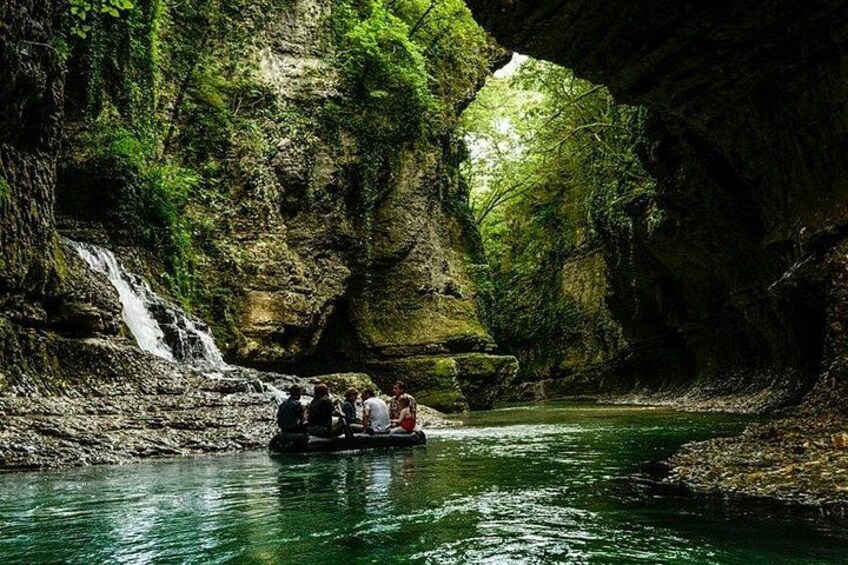 A group of people on a boat in a river canyon with a waterfall. 3