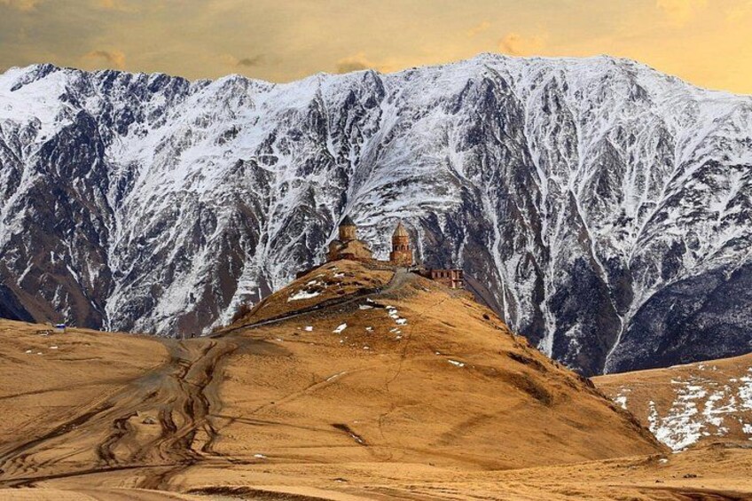 A snow-covered mountain range with a small building on a hill. 2