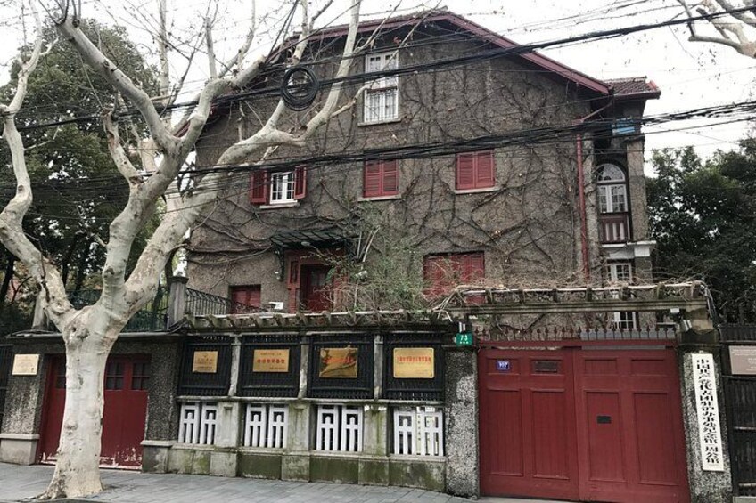 Un edificio con contraventanas rojas, un árbol en la fachada y un portón de color rojo. 4