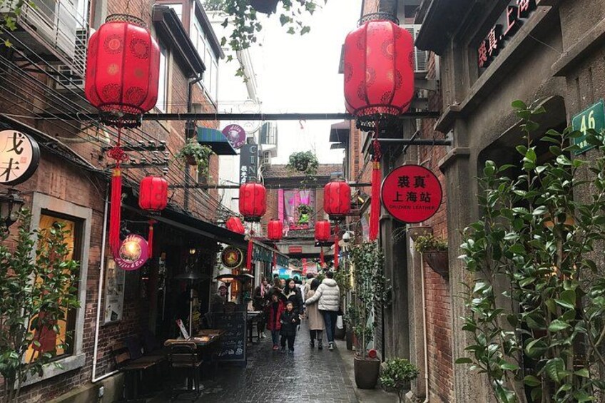 Un callejón estrecho con faroles rojos, edificios de ladrillo y carteles en un idioma extranjero. 2
