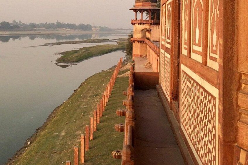A riverside view with a building featuring ornate architecture and a pathway leading to a bridge. 5