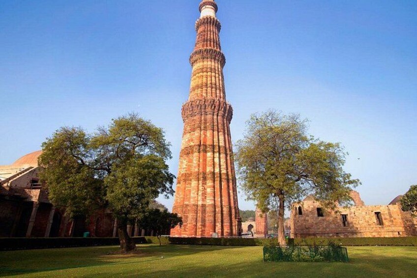 A tall, historic tower with a spiral minaret, surrounded by trees and ancient ruins. 2