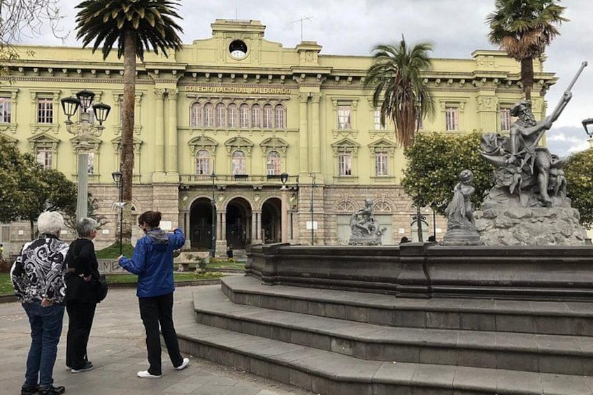 Ein großes Gebäude mit einer Statue eines Mannes, der ein Schwert hält, Palmen und einem Brunnen. 1