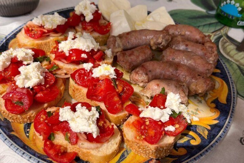 Un piatto con bruschette condite con pomodori e formaggio, e salsicce. 2