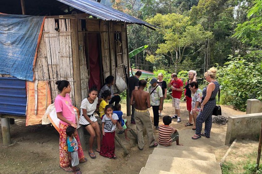 A group of people gathered around a rustic wooden structure in a tropical setting. 5
