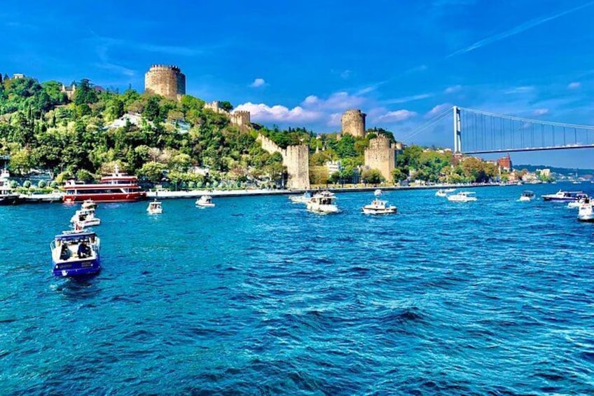 A coastal city with a historic castle, a bridge, and boats on the water. 4