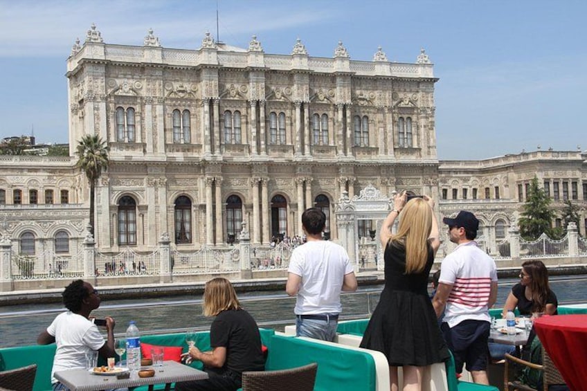 A group of people dining at an outdoor restaurant with a historic building in the background. 2