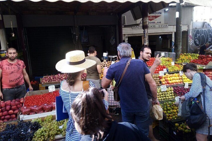 Een levendige openluchtmarkt waar mensen boodschappen doen voor fruit en groenten. 4