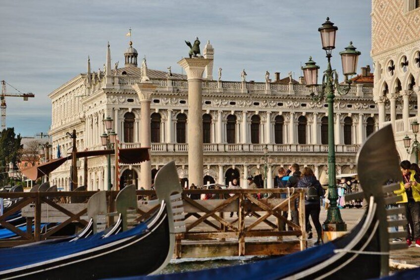 Gondolas docked at a canal with a historic building in the background. 5