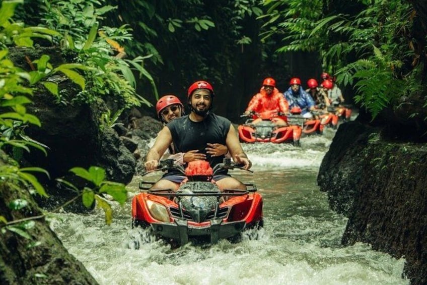 People riding red watercraft through a narrow, rocky waterway surrounded by dense greenery. 3