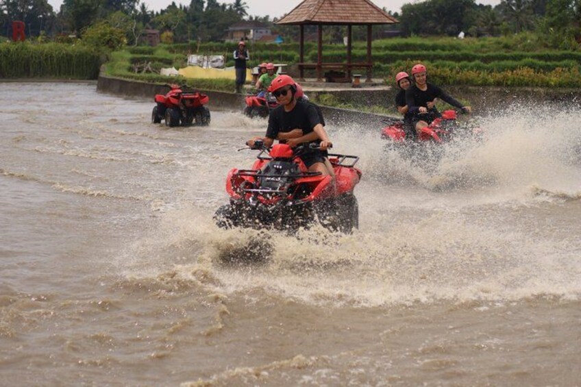 Personas conduciendo vehículos todo terreno rojos por una zona inundada. 4