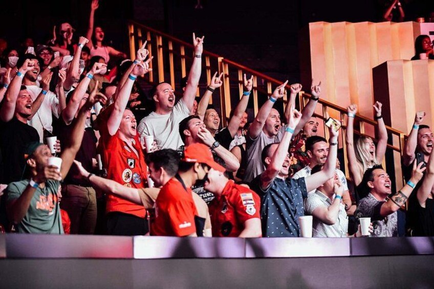 A crowd of people at a concert with raised hands and cheering. 4