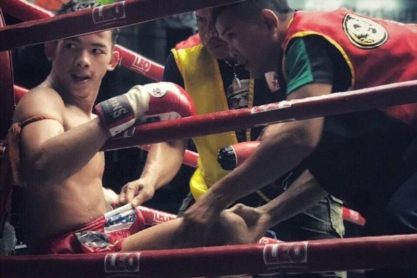 A boxing match in progress with a boxer in red shorts and a referee in yellow. 2